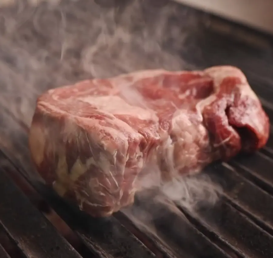 Bife de La Cabrera ahumándose sobre la parrilla