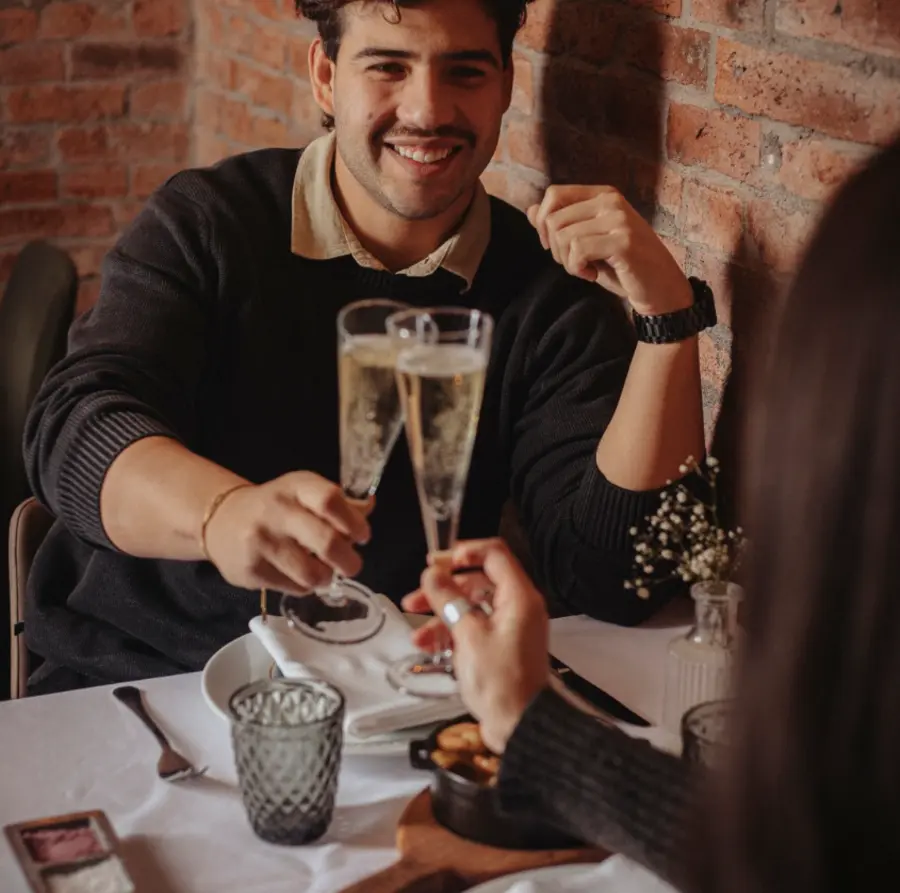 Brindis con espumante contra el muro de ladrillo