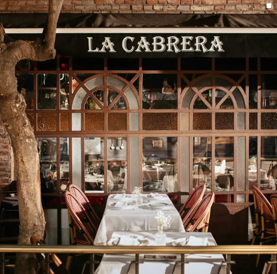 Fachada de La Cabrera: ladrillo, toldo negro y ventanas de arco