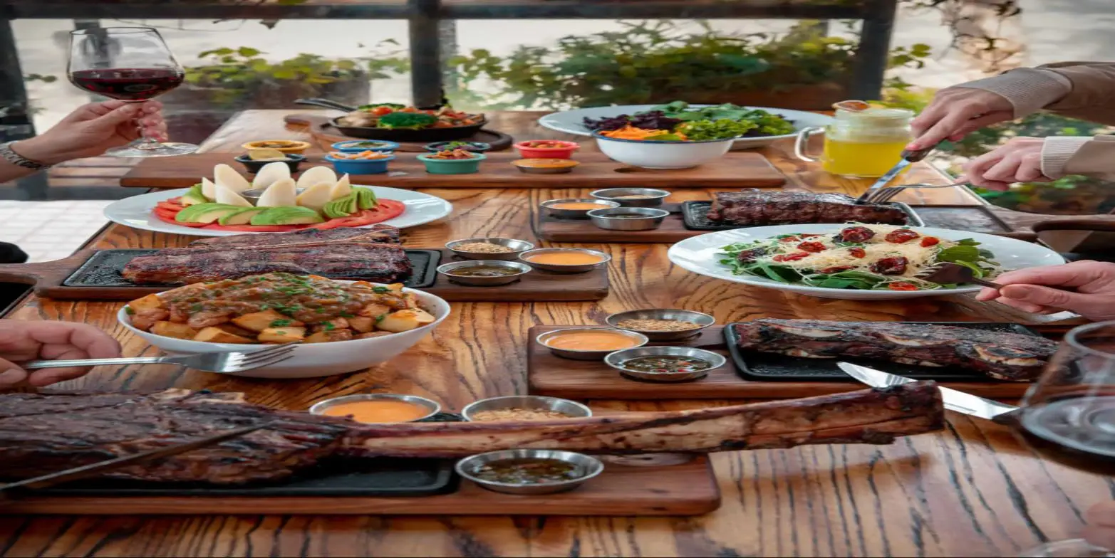 Mesa larga con cortes, ensaladas y tomahawk